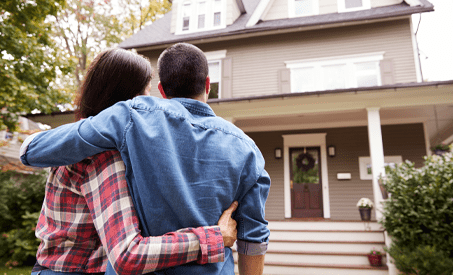 Couple hugging and looking at their new home.
