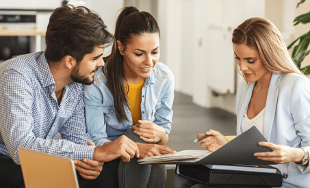 Una pareja mirando documentos con un empleado.