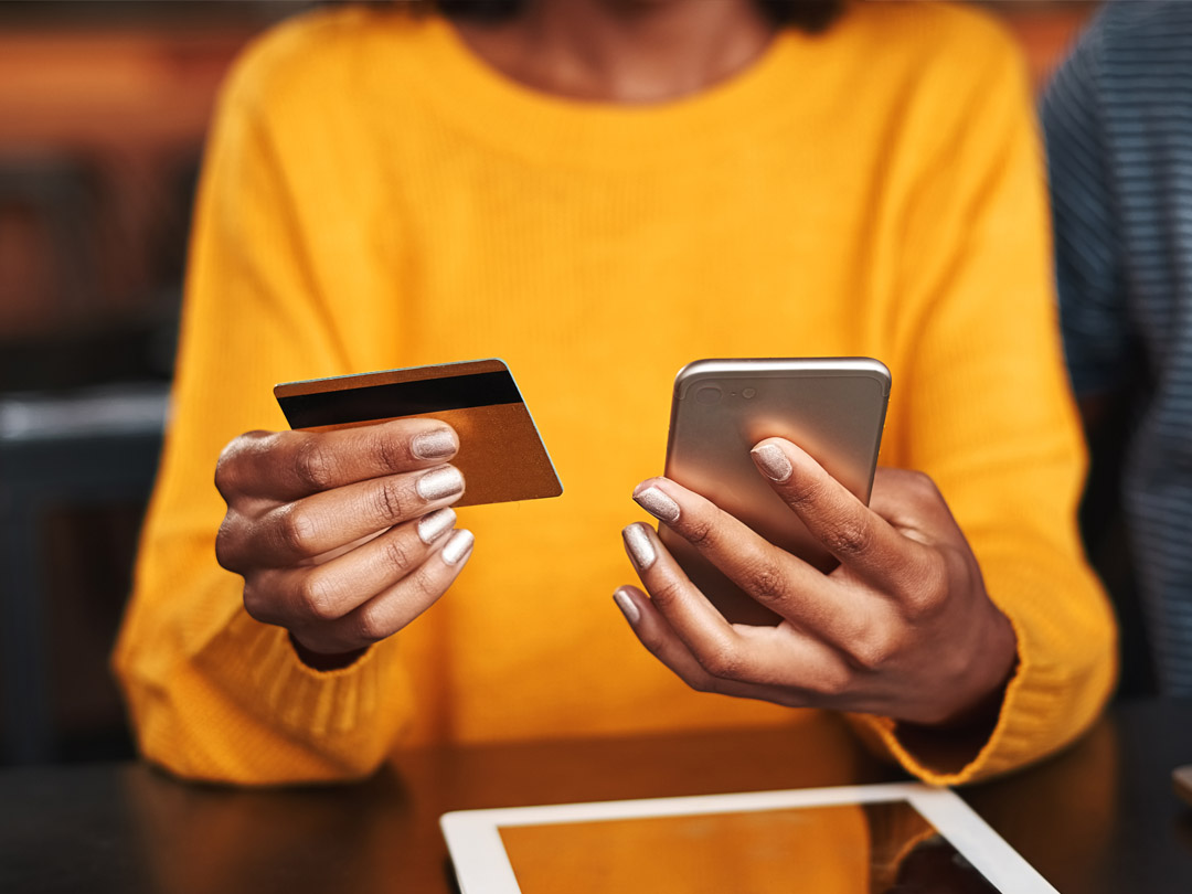 Woman holding her phone and her debit card.