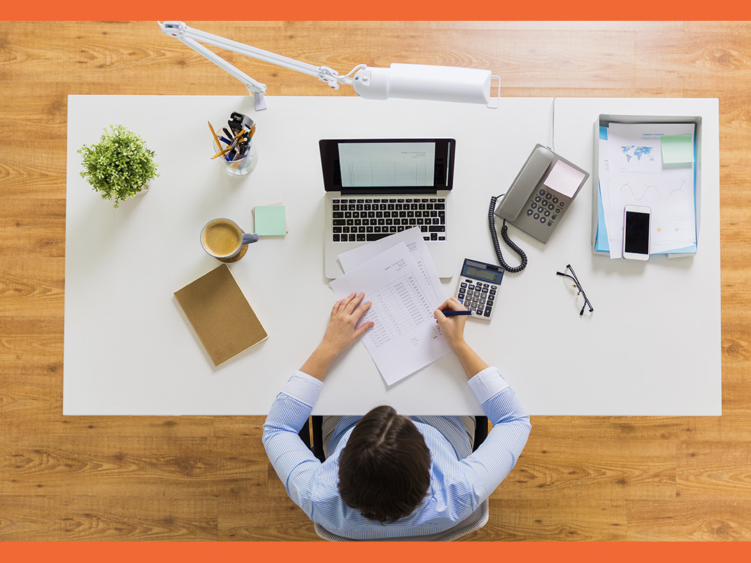 Person writing and calculating taxes on a desk.