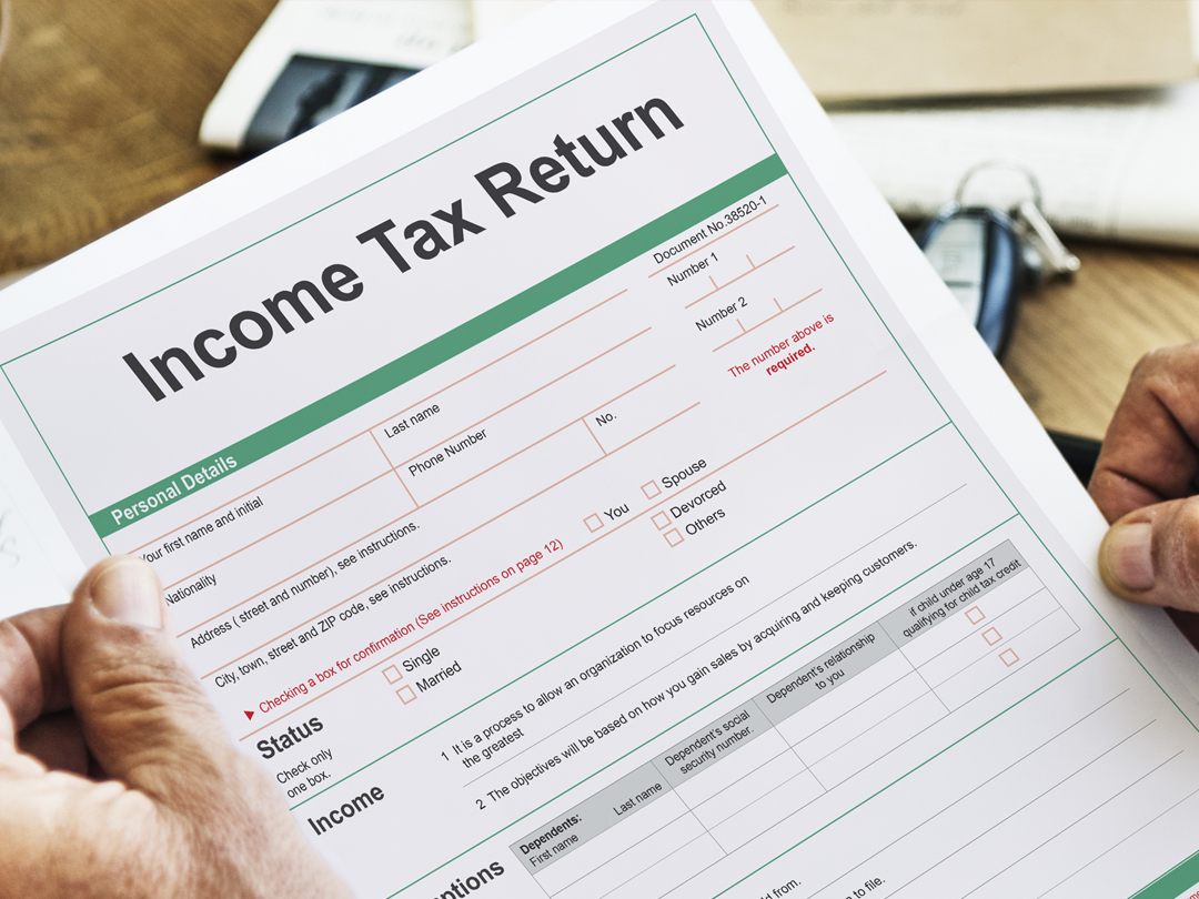 Older man holding and reading an income tax return form.