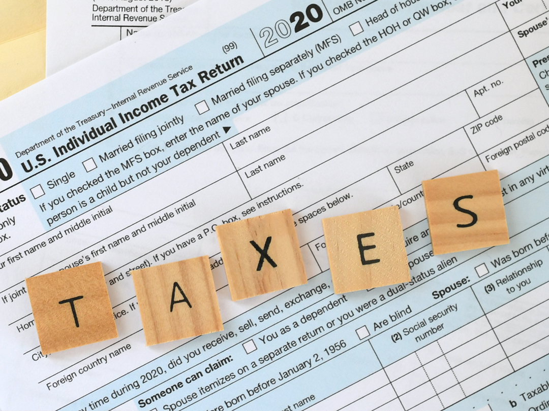 Wooden blocks spelling "TAXES" on a tax return form.