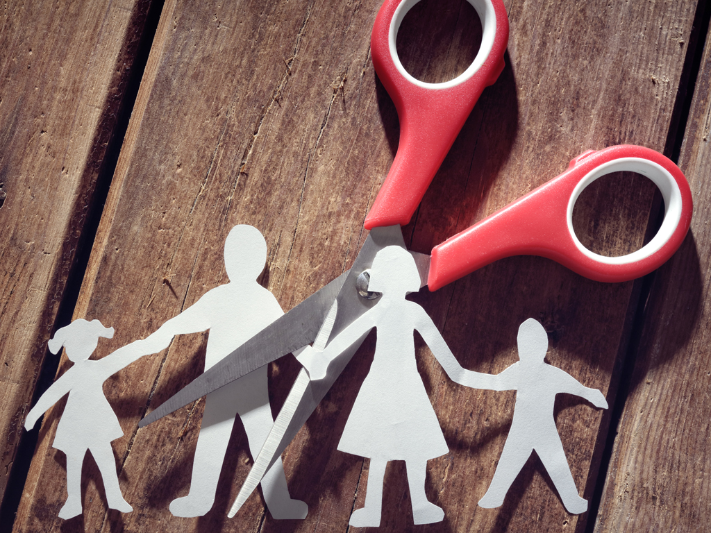 Una familia de papel recortada con tijeras que cortan entre los padres.